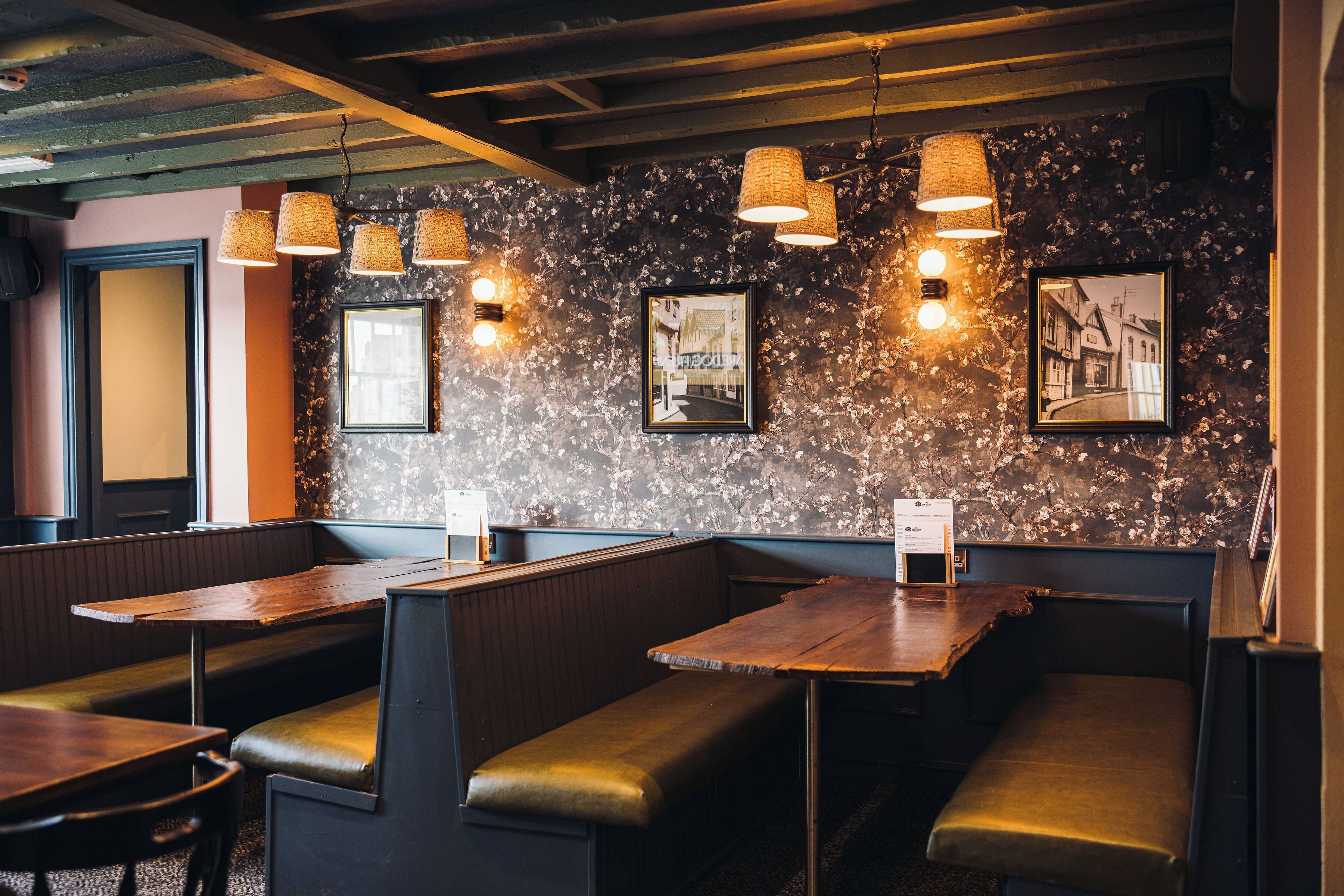 A restaurant interior with wooden booths, woven pendant lights, and framed pictures on the wall.