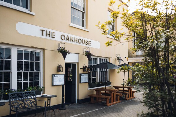 A building with a sign reading 'The Oakhouse' and outdoor seating with tables and chairs.