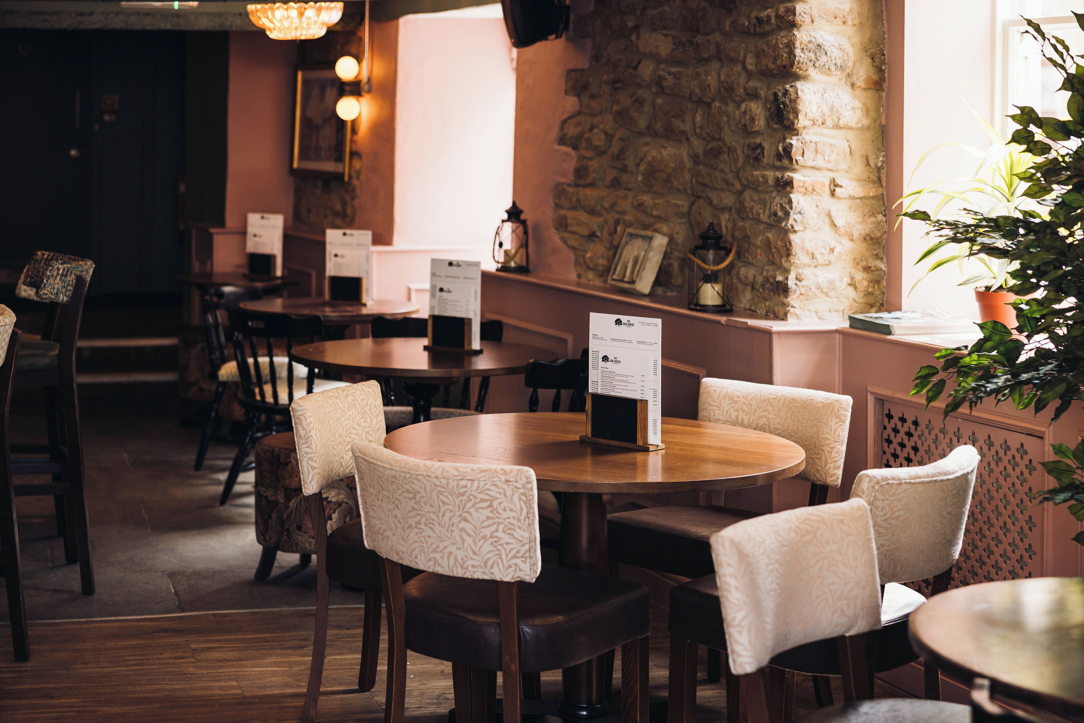 A restaurant interior with round tables, chairs, and menu stands.
