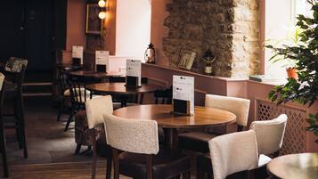 A restaurant interior with round tables, chairs, and menu stands.