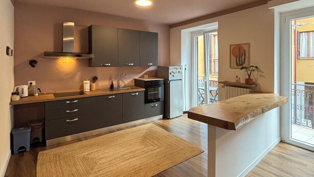 A modern kitchen with dark cabinets, a stainless steel range hood, and a wooden countertop. - House Eliana apartment Moon A stone's throw from the lake (Meina)