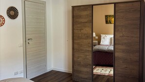 A bedroom with a bed, wardrobe, and an air conditioning unit. - House Eliana apartment Moon A stone's throw from the lake (Meina)