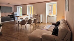 A spacious living area with a dining table, chairs, a sofa, and a potted plant. - House Eliana apartment Moon A stone's throw from the lake (Meina)