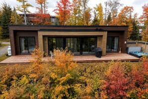 Een modern huis met een terras, grote schuifdeuren en een jacuzzi.