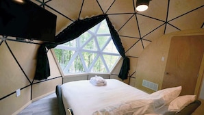 A room with a bed, a window with a geometric view, and a television mounted on the wall.