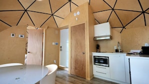 A modern kitchen with a built-in oven, white cabinetry, and a geometric ceiling design.