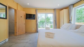 Un dormitorio con cama, televisor, balcón y puerta corredera.