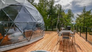 A transparent geodesic dome structure, a wooden deck, and a hot tub. - Bel Air Tremblant DÔME CLASSIQUE: 1 LIT KING, JACUZZI ET SAUNA-450PI (La Conception)
