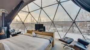 A dome-shaped room with a bed, a television, and a fireplace. - Bel Air Tremblant DÔME CLASSIQUE: 1 LIT KING, JACUZZI ET SAUNA-450PI (La Conception)