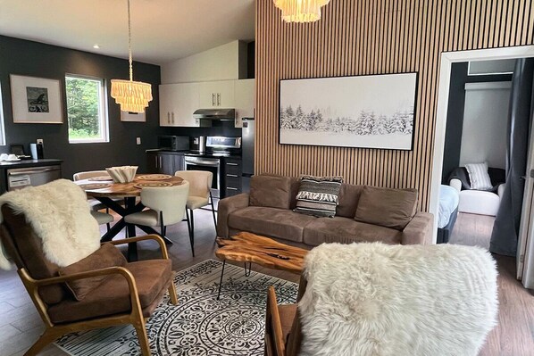 Ein modernes Wohnzimmer mit einer Couch, Sesseln, einem Couchtisch und einem Essbereich.
