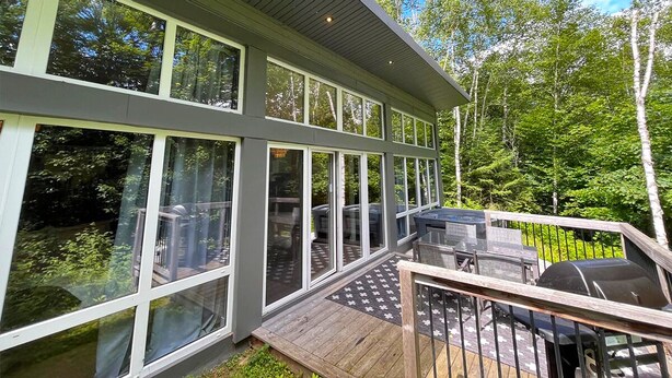 A modern house with large windows, a deck, and a barbecue grill. - Bel Air Tremblant L'ETOILE : 2 CHAMBRES, JACUZZI PRIVÉ (La Conception)
