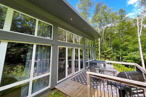 Ein modernes Haus mit großen Fenstern, einer Terrasse und einem Grill.