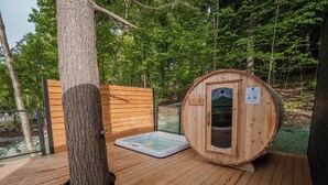 A sauna with a wooden exterior, a glass door, and a wooden deck.