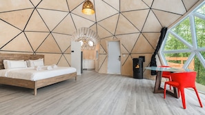A modern bedroom with a geometric wall design, a bed, a table with red chairs, and a fireplace. - Bel Air Tremblant MICKEY DÔME : 1 LIT KING, JACUZZI ET SAUNA (La Conception)