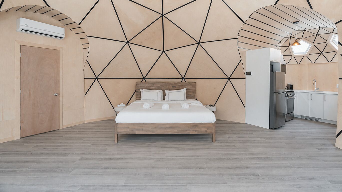 Ein modernes Schlafzimmer mit geometrischem Wanddesign, einem hölzernen Bett und einer Küchenzeile.