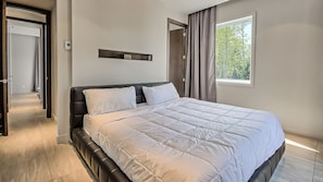 Une chambre moderne avec un grand lit, un radiateur intégré et une fenêtre avec des rideaux.