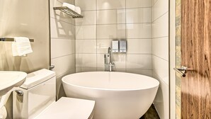 Ein modernes Badezimmer mit einer freistehenden Badewanne, einer Toilette und einem Waschbecken.