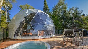 A geodesic dome structure with a hot tub and outdoor furniture on a wooden deck. - Bel Air Tremblant DÔME MEZZANINE : 1 KING, 2 SIMPLE, JACUZZI, SAUNA-450PI (La Conception)