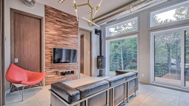 Un salon moderne avec un téléviseur, une cheminée et une grande fenêtre.