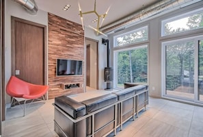Ein modernes Wohnzimmer mit Fernseher, Kamin und großem Fenster.