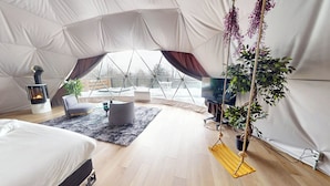 A tented room with a fireplace, a sofa, a TV, and a hanging plant.