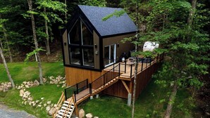 A cabin with a deck, a staircase, and a large window. - Bel Air Tremblant CALAFATE : 1 CHAMBRE, JACUZZI, SAUNA (La Conception)