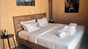 A neatly made bed with white linens and pillows, a wooden headboard, and a small bedside table with a remote control. - Bel Air Tremblant CALAFATE : 1 CHAMBRE, JACUZZI, SAUNA (La Conception)