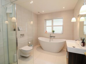 A modern bathroom with a glass shower enclosure, a freestanding toilet, a freestanding bathtub, and a vanity with a sink. - Sunnyside (Courtown)