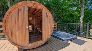 A wooden sauna with a hot tub, surrounded by a wooden deck and glass railing. - Bel Air Tremblant DÔME DELUXE : 1 LIT KING, JACUZZI, SAUNA-700PI (La Conception)