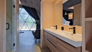 A modern bathroom with a large mirror, two sinks, and a shower area with a glass door. - Bel Air Tremblant DÔME DELUXE : 1 LIT KING, JACUZZI, SAUNA-700PI (La Conception)