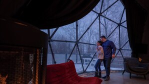 A room with a large window, a red sofa, and a fireplace. - Bel Air Tremblant DÔME DELUXE : 1 LIT KING, JACUZZI, SAUNA-700PI (La Conception)