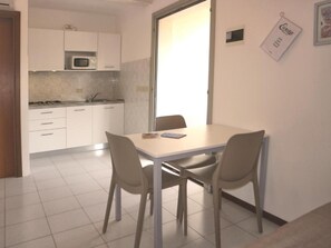 Une cuisine compacte avec des meubles blancs, un four à micro-ondes et une table à manger avec des chaises.