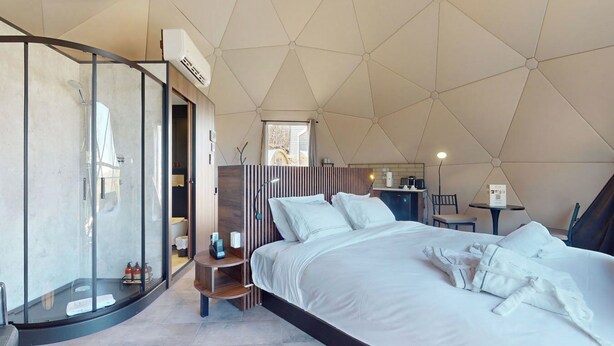 Ein modernes Schlafzimmer mit einem großen Bett, einer gläsernen Dusche und einer Küchenzeile.