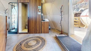 Ein modernes Interieur mit einem Holzbüro, einer Glasdusche und Blick auf eine felsige Landschaft.