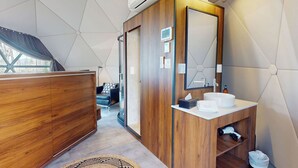 Ein modernes Badezimmer mit einem Holz-Waschtisch, einem großen Spiegel und einem weißen Waschbecken.