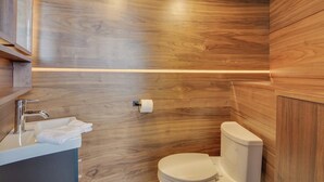A modern bathroom with wooden walls, a white sink, and a toilet.