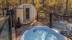 A wooden hot tub on a deck with a sauna and a glass-enclosed room. - Bel Air Tremblant ROUND LOFT : 1 LIT KING, JACUZZI ET SAUNA (La Conception)