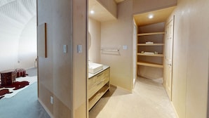 A narrow walk-in closet with a wooden vanity, shelves, and a hanging rod.