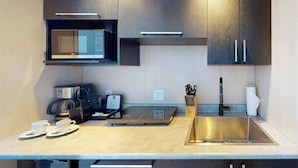 A compact kitchen with a microwave, coffee machine, and a sink.