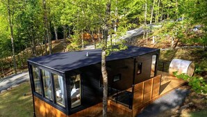 Une cabane avec une façade en verre, un revêtement extérieur en bois et une petite terrasse.