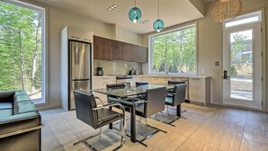 A modern kitchen with a dining area, large windows, and a view of the outdoors.