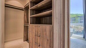 A walk-in closet with multiple wooden shelves and drawers.