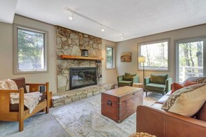 A cozy living room with a stone fireplace, large windows, and comfortable seating. - Stratton; 8 min. Swimming; 2 min. Pet Friendly (Winhall)