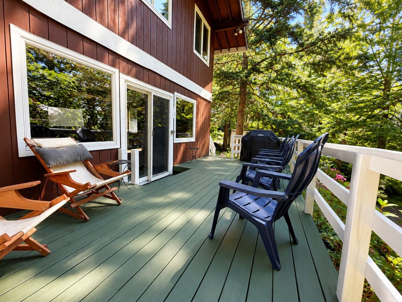 Une terrasse en bois avec des meubles d’extérieur, notamment des chaises et une table, et un bâtiment doté de grandes fenêtres et d’une porte.