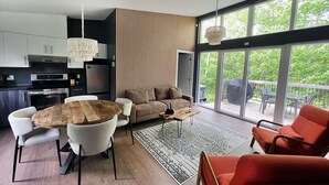 Una sala de estar moderna con una mesa de comedor de madera, un sofá y un sillón rojo.