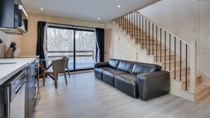 Una cocina moderna con comedor, un sofá de cuero y una escalera.