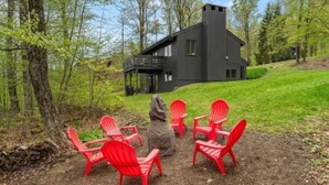 A cabin with a balcony, surrounded by a forest, and four red chairs arranged in a circle. - Stratton; walk on/off, shuttle Rt, pool table, shuffle puck, darts, dogs OK (Winhall)