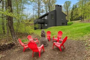 A cabin with a balcony, surrounded by a forest, and four red chairs arranged in a circle. - Stratton; walk on/off, shuttle Rt, pool table, shuffle puck, darts, dogs OK (Winhall)