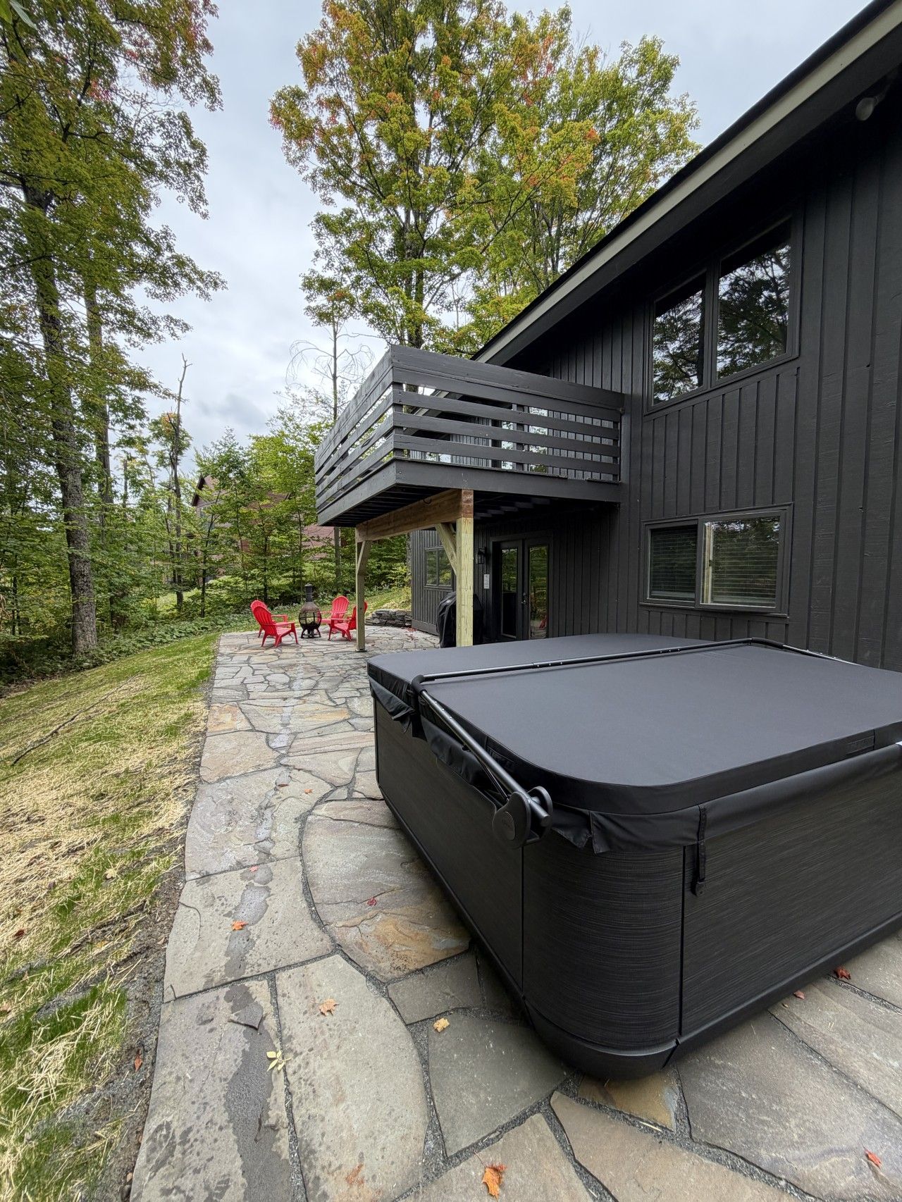 A modern house with a stone patio, a hot tub, and a deck.