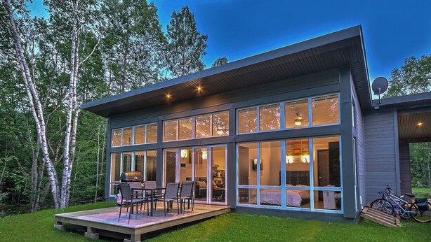 Ein modernes Haus mit großen Fenstern, einer Terrasse und einer Satellitenschüssel.